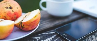 мобильный телефон и тарелка с яблоками на деревянном столе